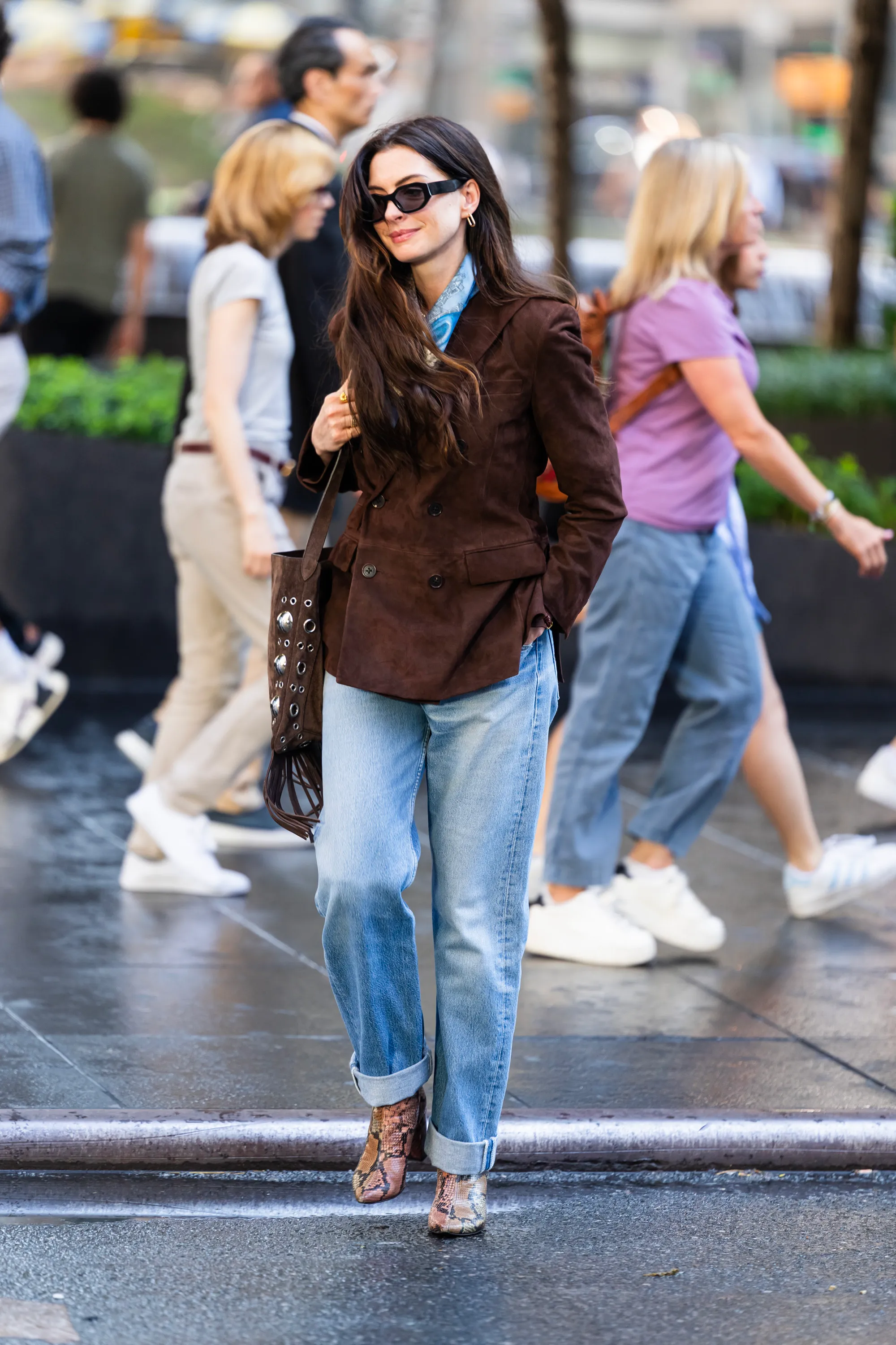 Anne Hathaway in The Devil Wears Prada 2 wearing Levi's vintage denim jeans with a brown suede jacket and snakeskin heeled boots