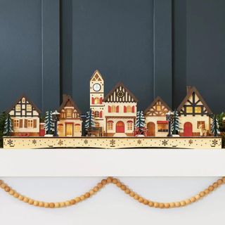 Best Choice Products Pre-Lit Wooden Christmas Village against a gray wall.