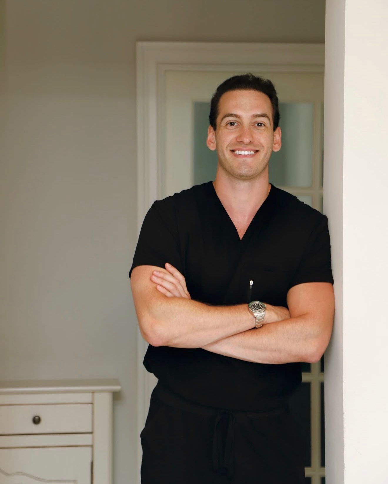 a headshot of a male doctor wearing black scrubs