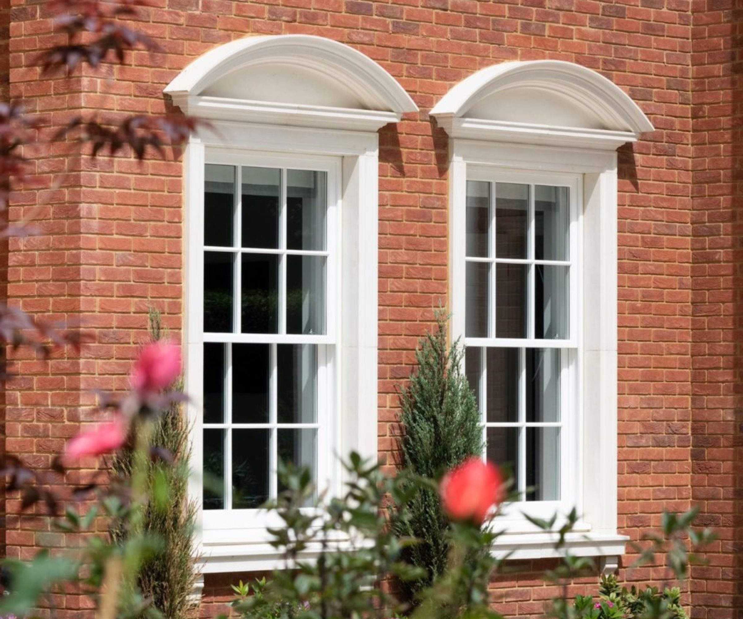 Elegant sash windows with white surrounds on a red brick façade, adding classic Georgian-inspired charm to a beautifully maintained home.