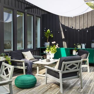 decked patio with shade sail, furniture and green metal storage