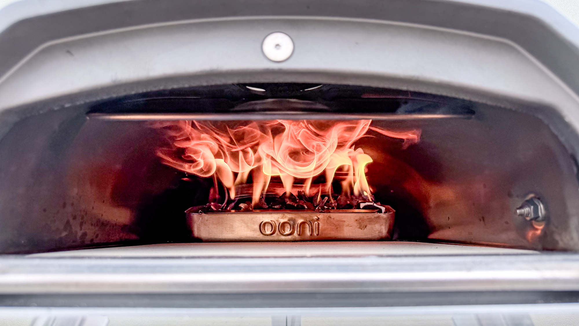 The Ooni Karu 2 pizza oven on with flames inside