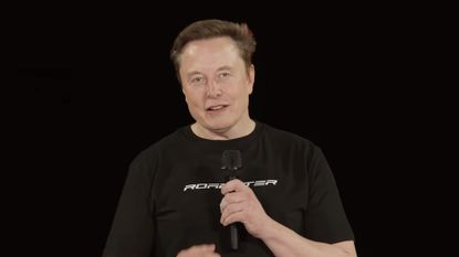 Elon Musk in black shirt on black background at Tesla Roadster event