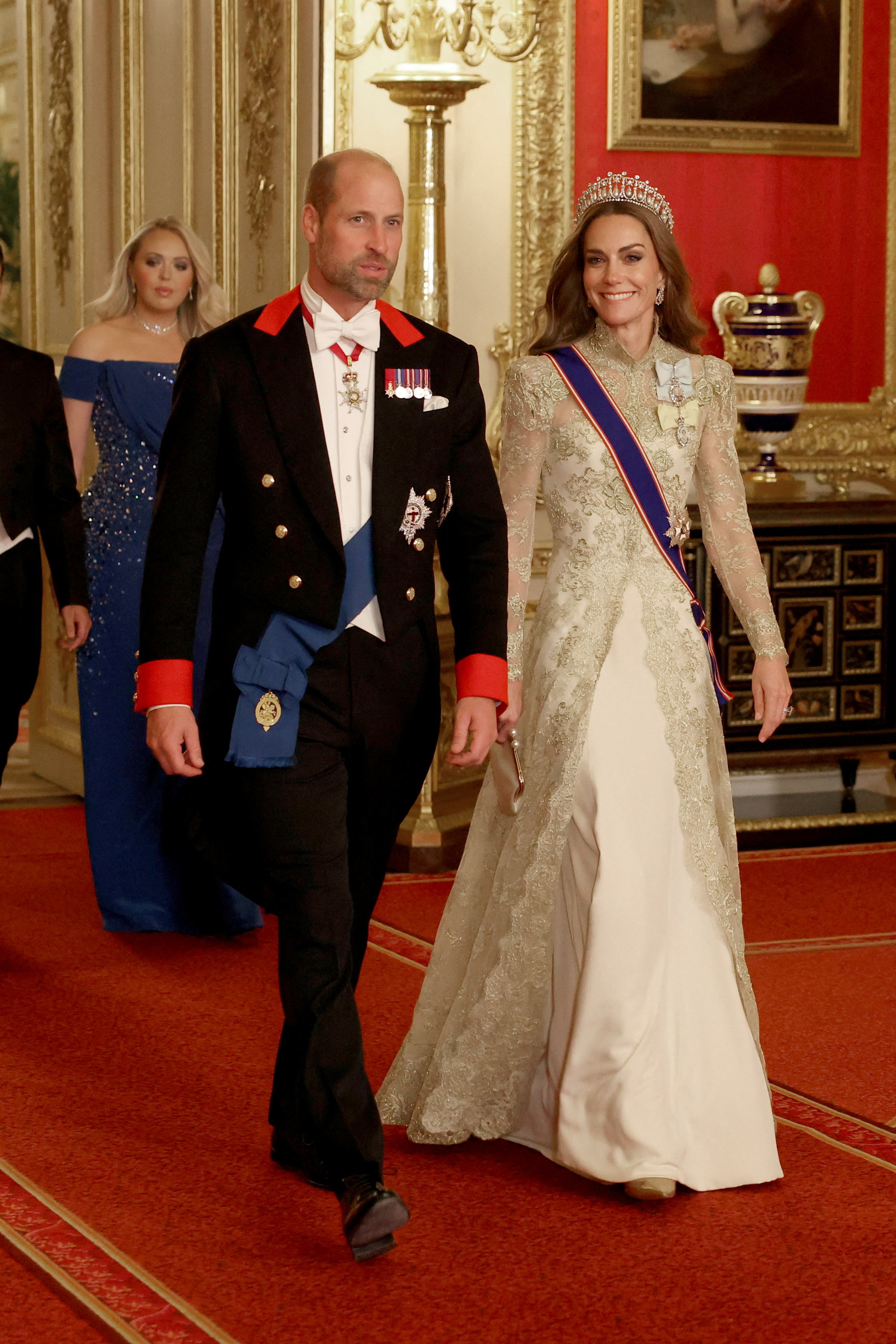 Princess Kate wearing a gold gown and tiara walking next to Prince William