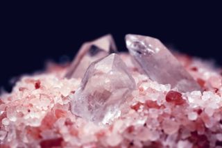 close up of quartz crystals nestled in pink salt to show how to cleanse crystals