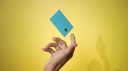 Close up male hand with credit card on yellow backdrop