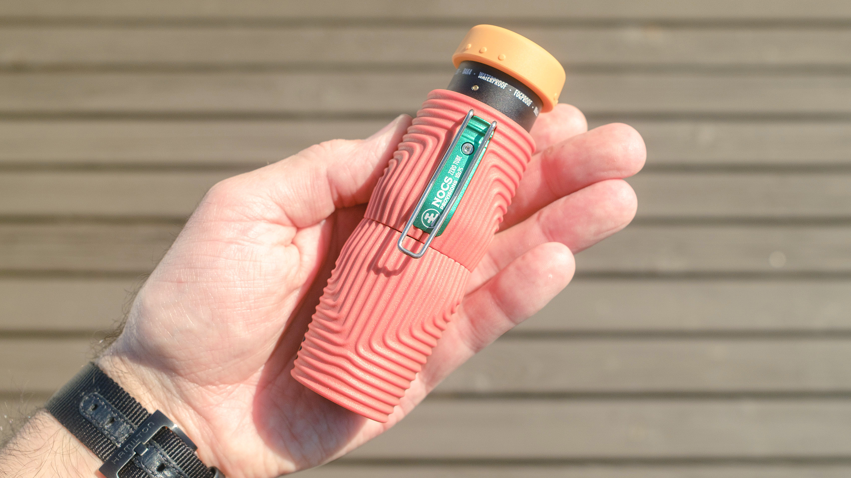 Nocs Zero Tube rugged monocular in orange shown close-up in a user's hand