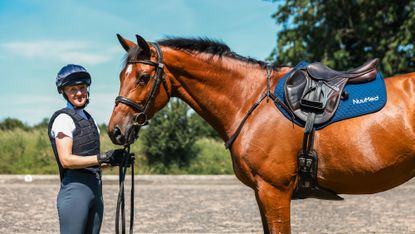 Eventer Eliza Bell holds a horse wearing a NuuMed saddlecloth