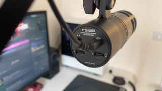 The Audio-Technica AT2040USB microphone on a mic stand in front of a monitor