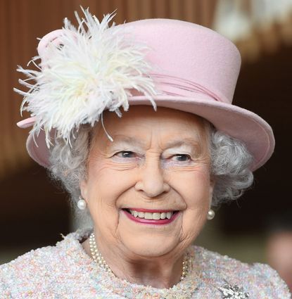 Queen Elizabeth wearing a pink hat and coat smiling