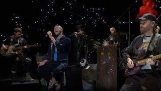 Coldplay performing with a starry background on SNL