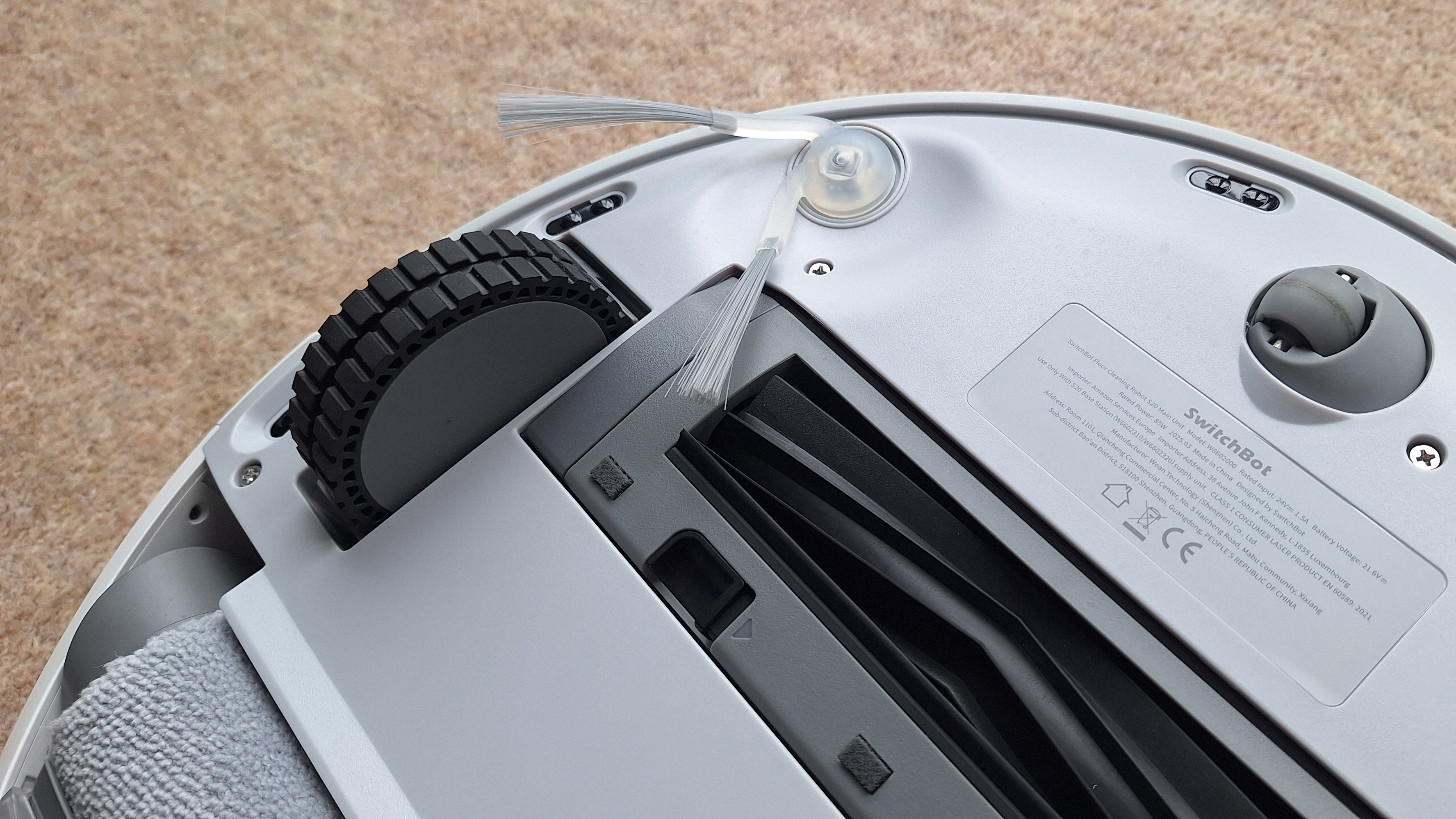 SwitchBot S20 robot vacuum flipped over to show wheels, side-sweeper brush and roller underneath