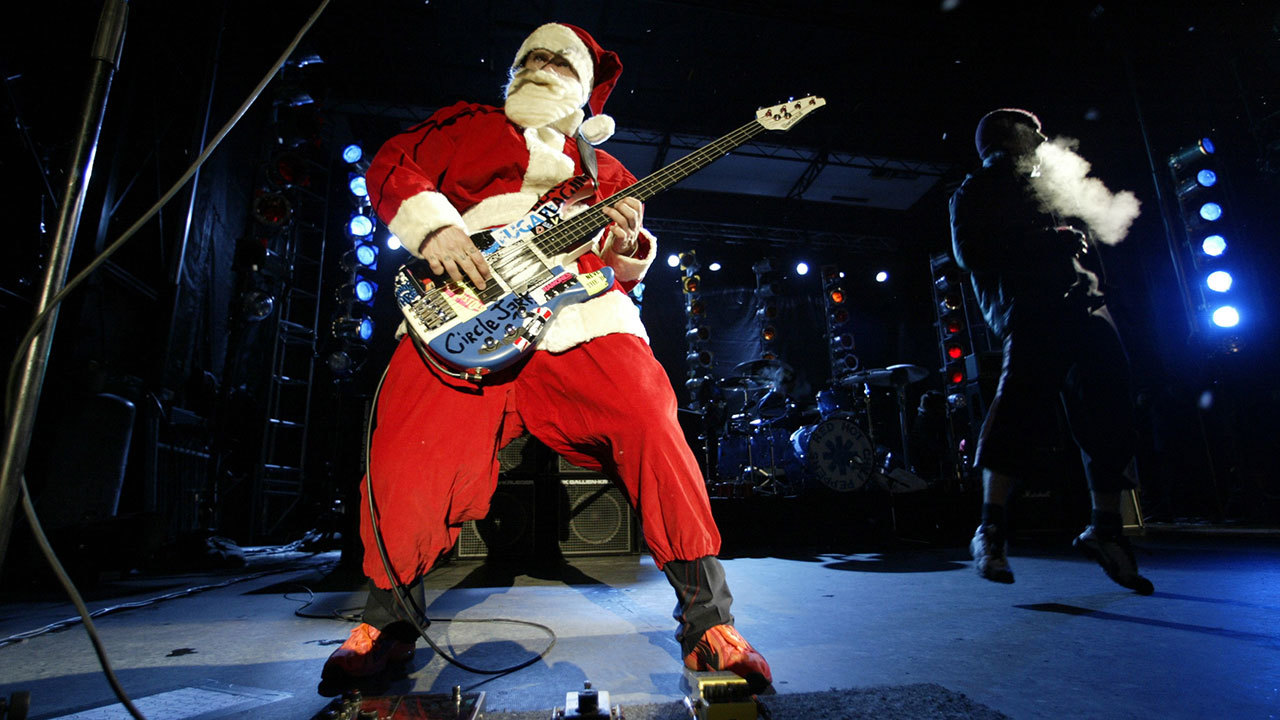 a photograph of flea dressed up as father christmas playing bass on stage