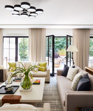 Cream sofas and lampshade, white coffee table, black framed windows