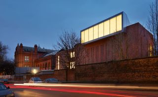 The Whitworth at the University of Manchester at night with cars parked in the street