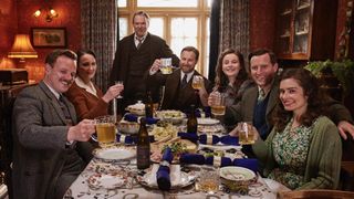 The cast of All Creatures Great and Small sit around a table and raise their glasses in the All Creatures Great and Small Christmas Special.