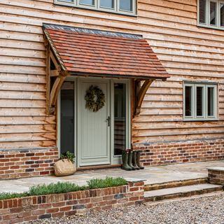 Natural stone patio walkway in front garden outside country home with wooden cladding