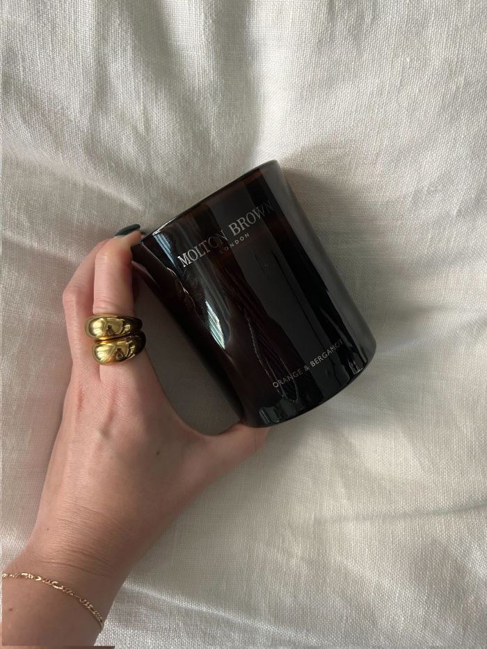 Junior beauty editor Grace Lindsay holding one of the best autumn candles against a white linen background