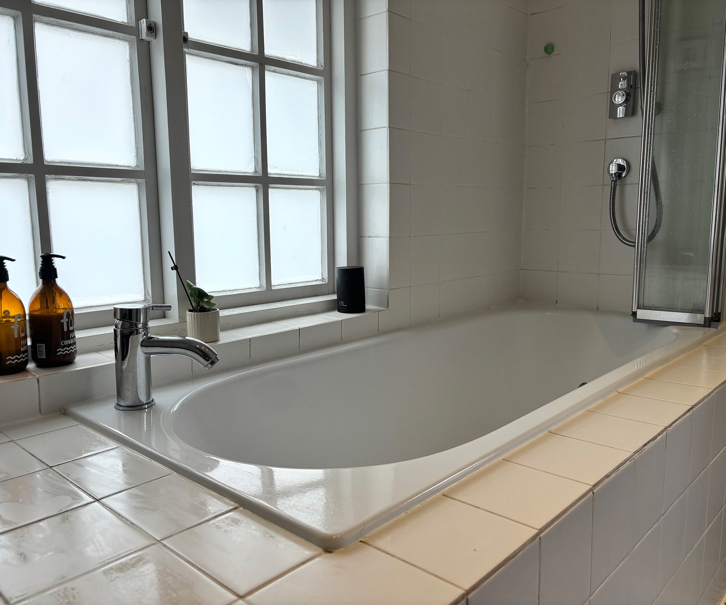 built-in bath with white tiles and monobloc tap