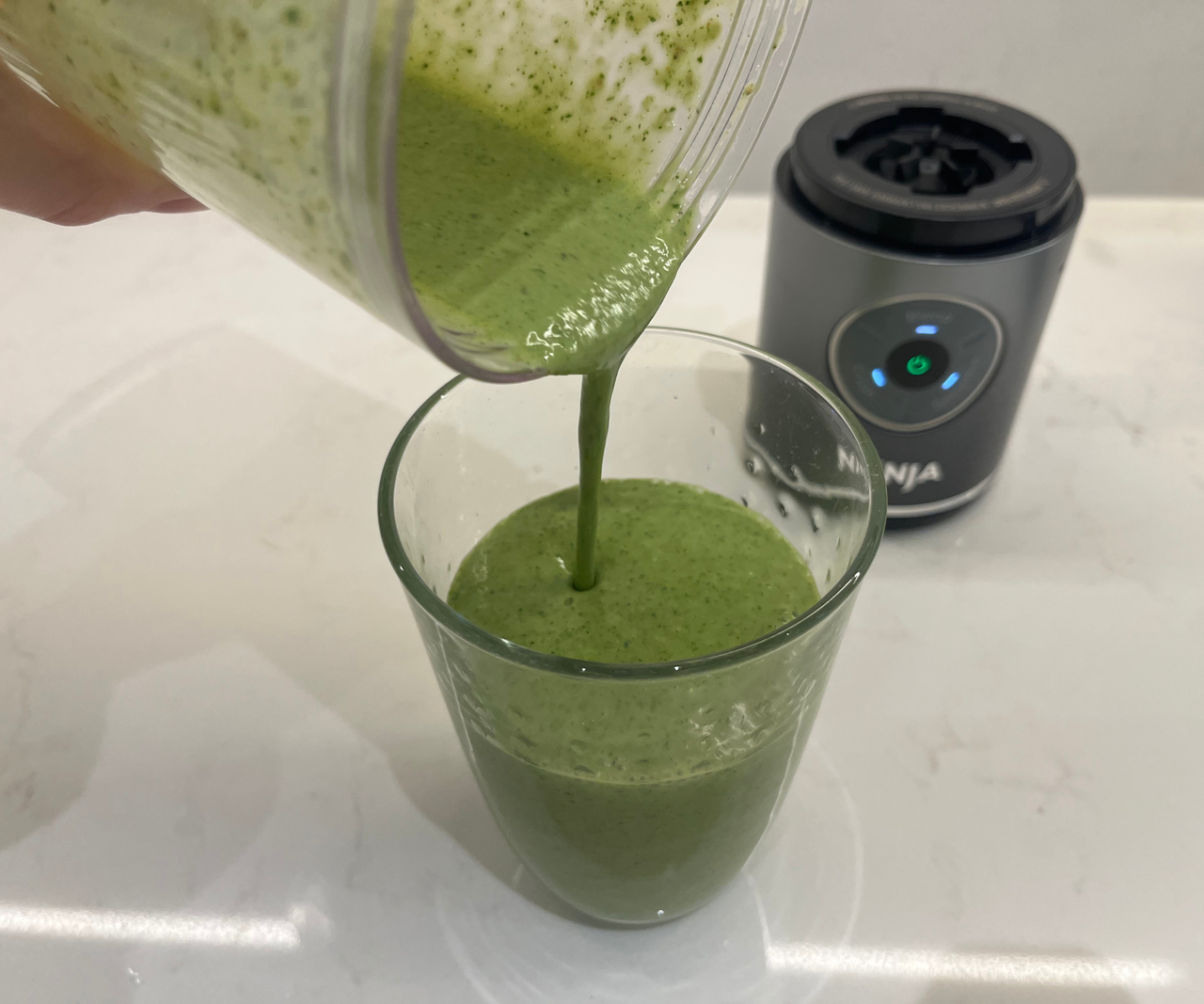 Pouring a green smoothie from the ninja blast max