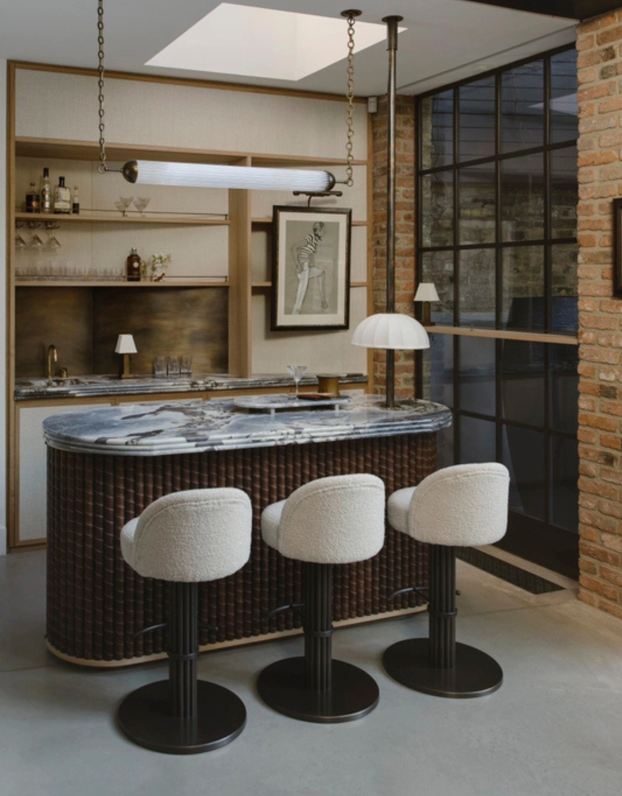 An indoor-outdoor home bar, with a marble counter, bar chairs, and a horizontal tube light