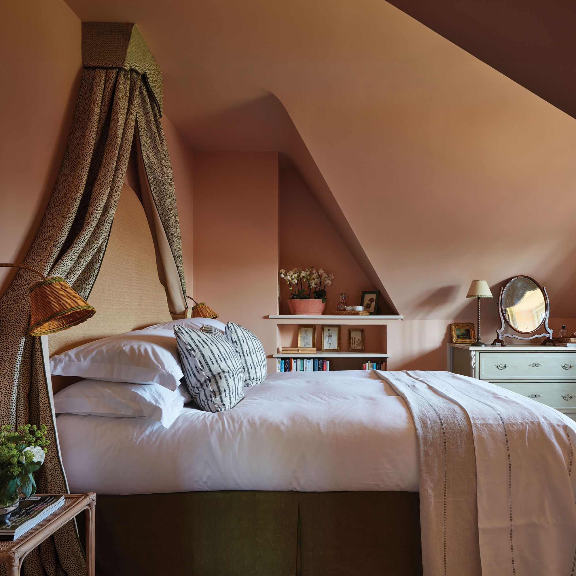 Dusty pink guest room with bedside lights, green chest of drawers and green bed frame