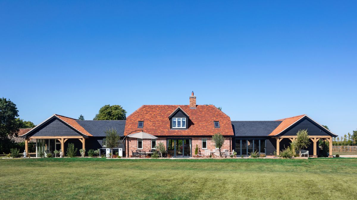 large brick self build property in centre flanked either side by black timber cladded sections 