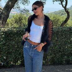 Hailey Bieber in white top, jeans, and black cardigan