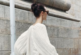 Zara model wearing an off-white wrinkled satin blouse with matching trousers and sunglasses.