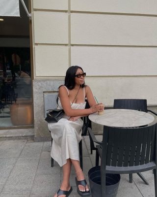 Woman at cafe wears beige dress and black flip flop sandals