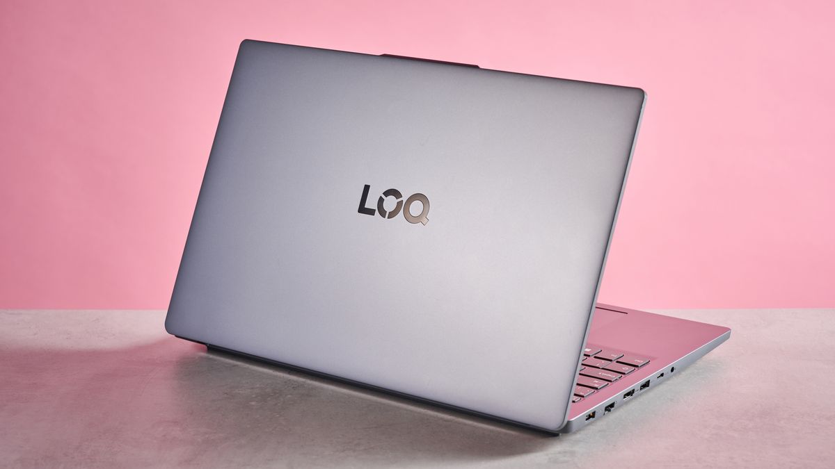 Rear three-quarter view of Lenovo LOQ Essential Gen 9 open on desk with pink wall in background