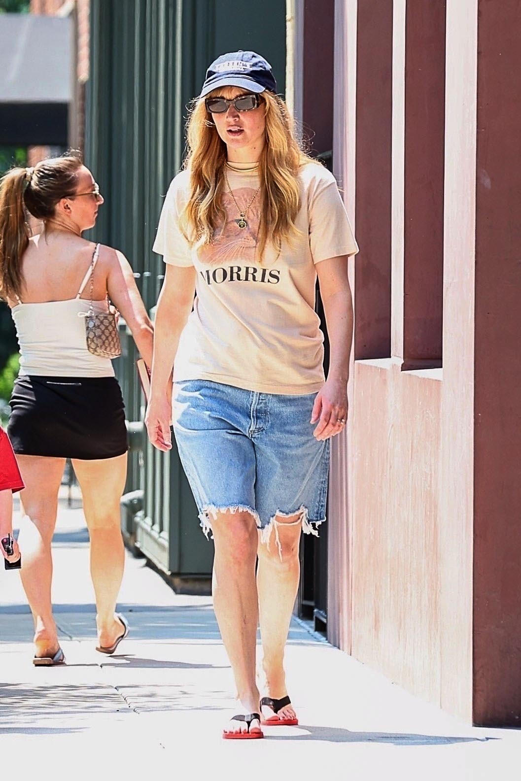 Jennifer Lawrence wearing a pair of denim bermuda shorts and the row dune flip flops