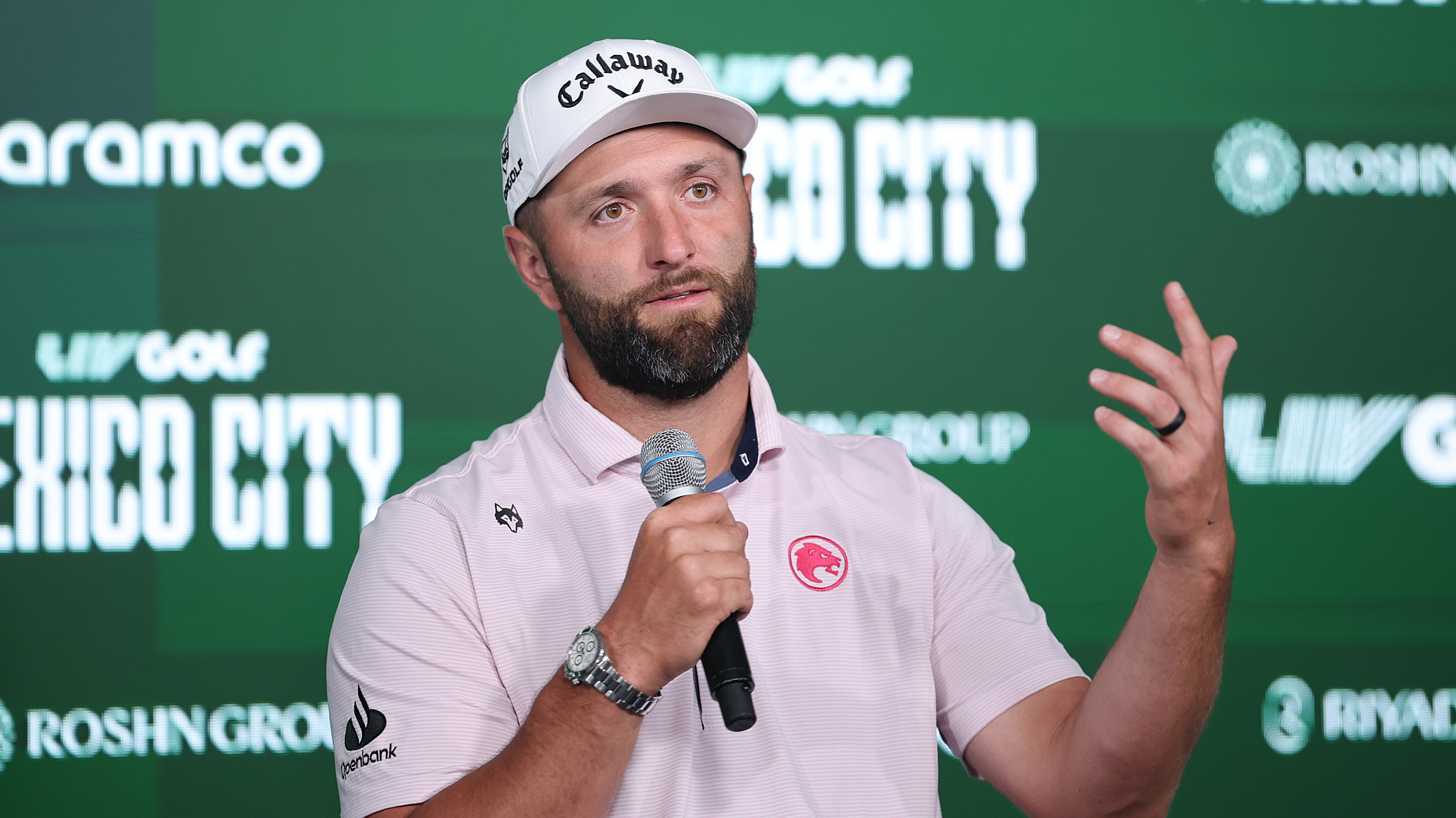 Jon Rahm speaks to the media in front of a green advertising background showing LIV Golf Mexico City, Aramco and Riyadh Air logos
