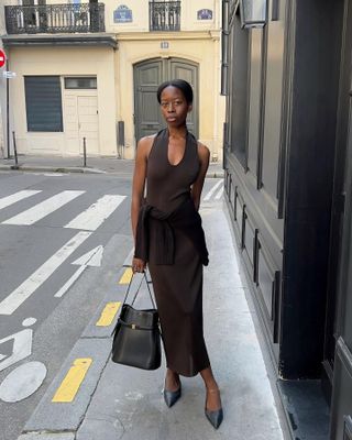 Woman wears brown knitted dress and black bag