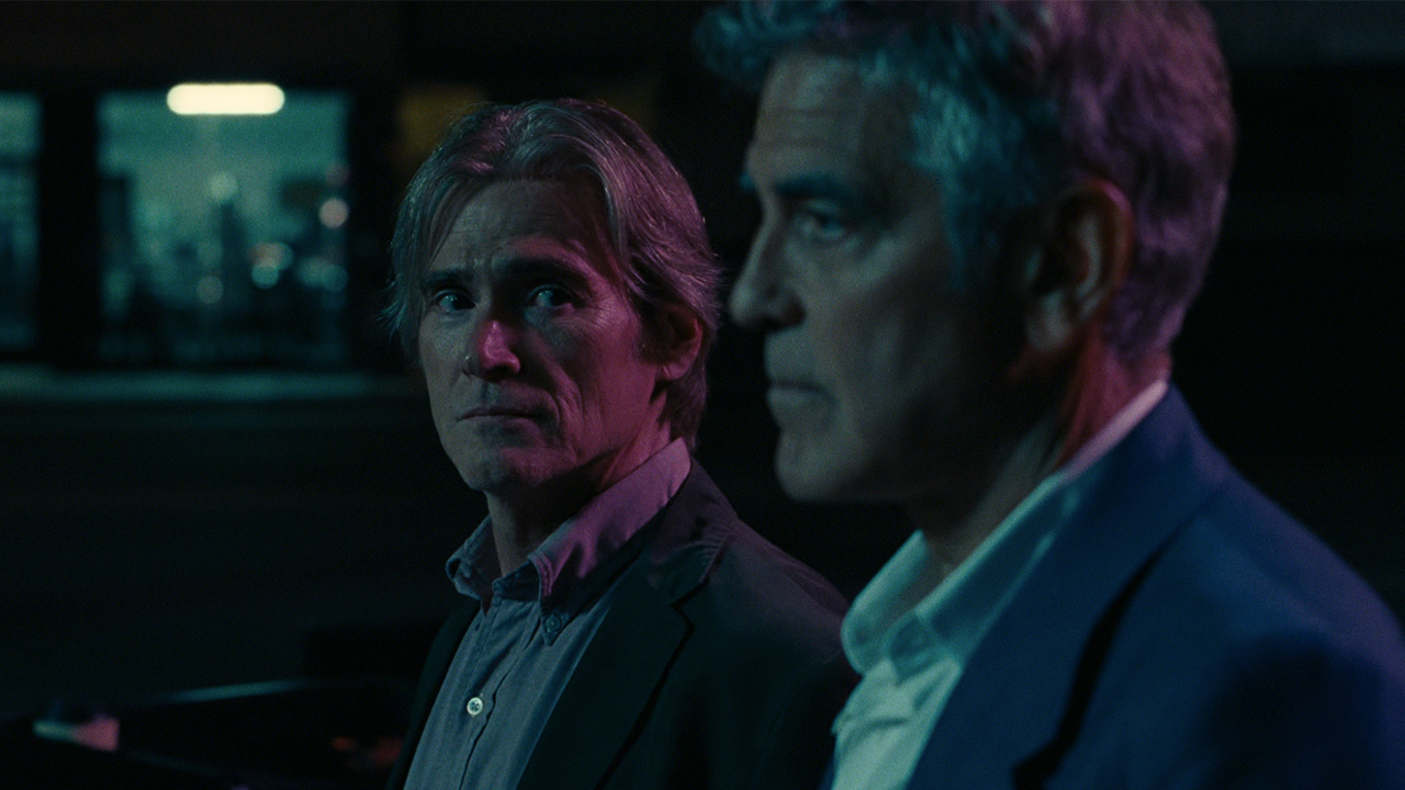George Clooney op de voorgrond met Billy Crudup achter hem, wantrouwend naar Jay Kelly kijkend.