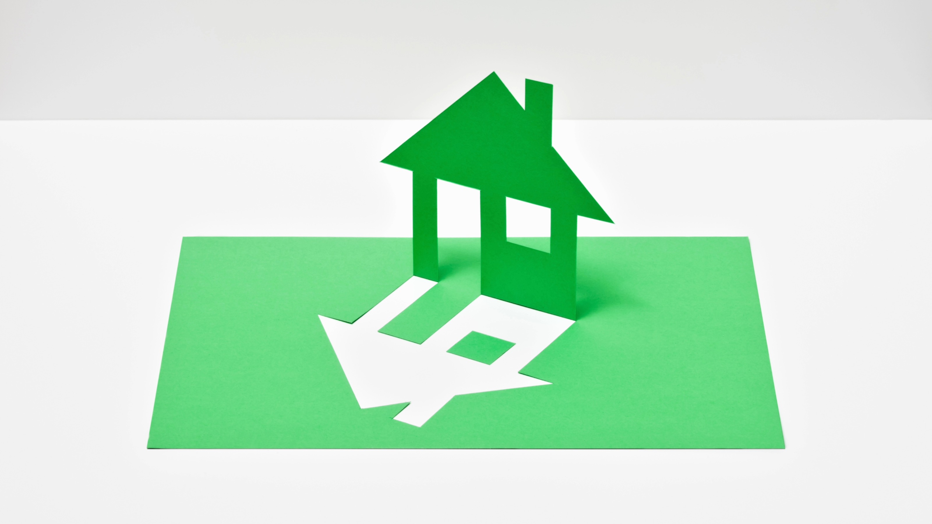 A house silhouette cut out from a sheet of green paper