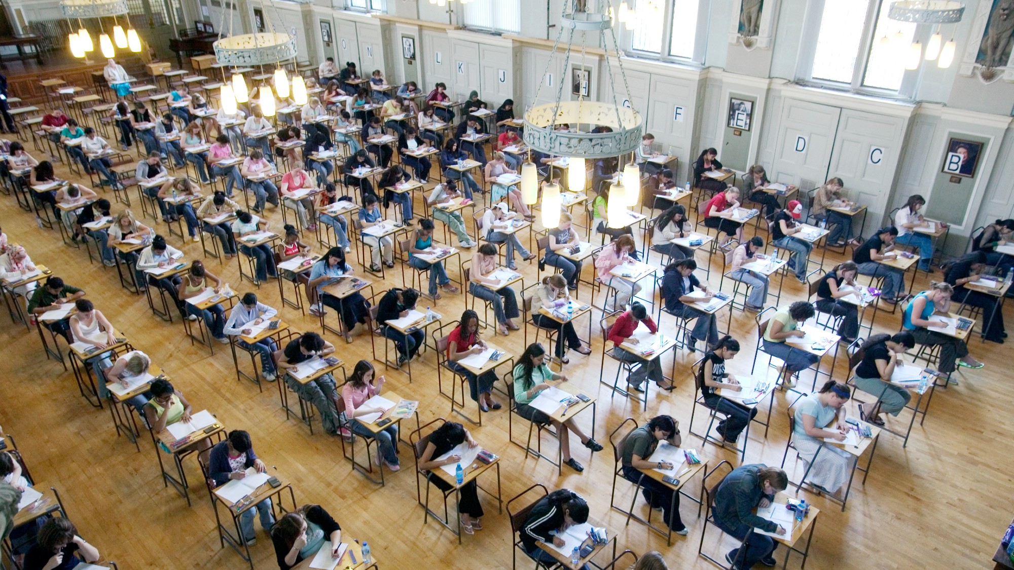 An exam hall full of students seated at desks, seen from above