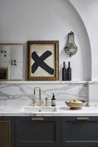 A kitchen sink with a marble backsplash and a chandelier
