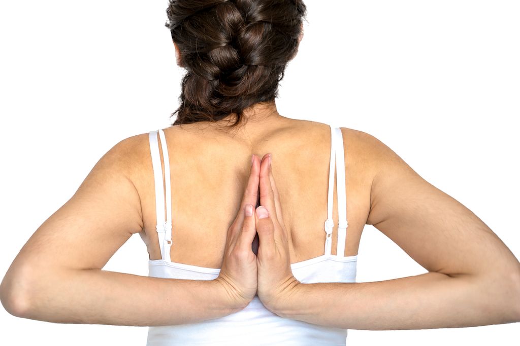 A woman with Ehlers-Danlos syndrome has the palms of her hands touching and pointed up, behind her back, between her shoulder blades.