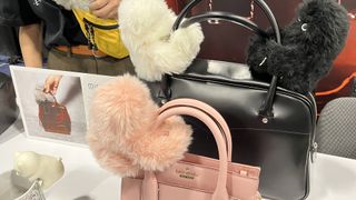 Three furry robots clipped onto handbags