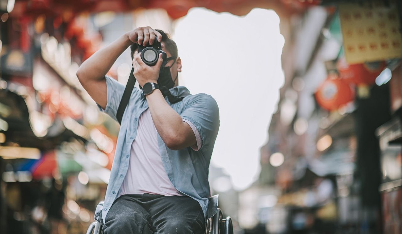 Man in wheelchair taking a picture of a street.