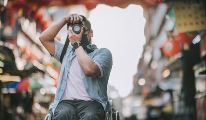 Man in wheelchair taking a picture of a street.
