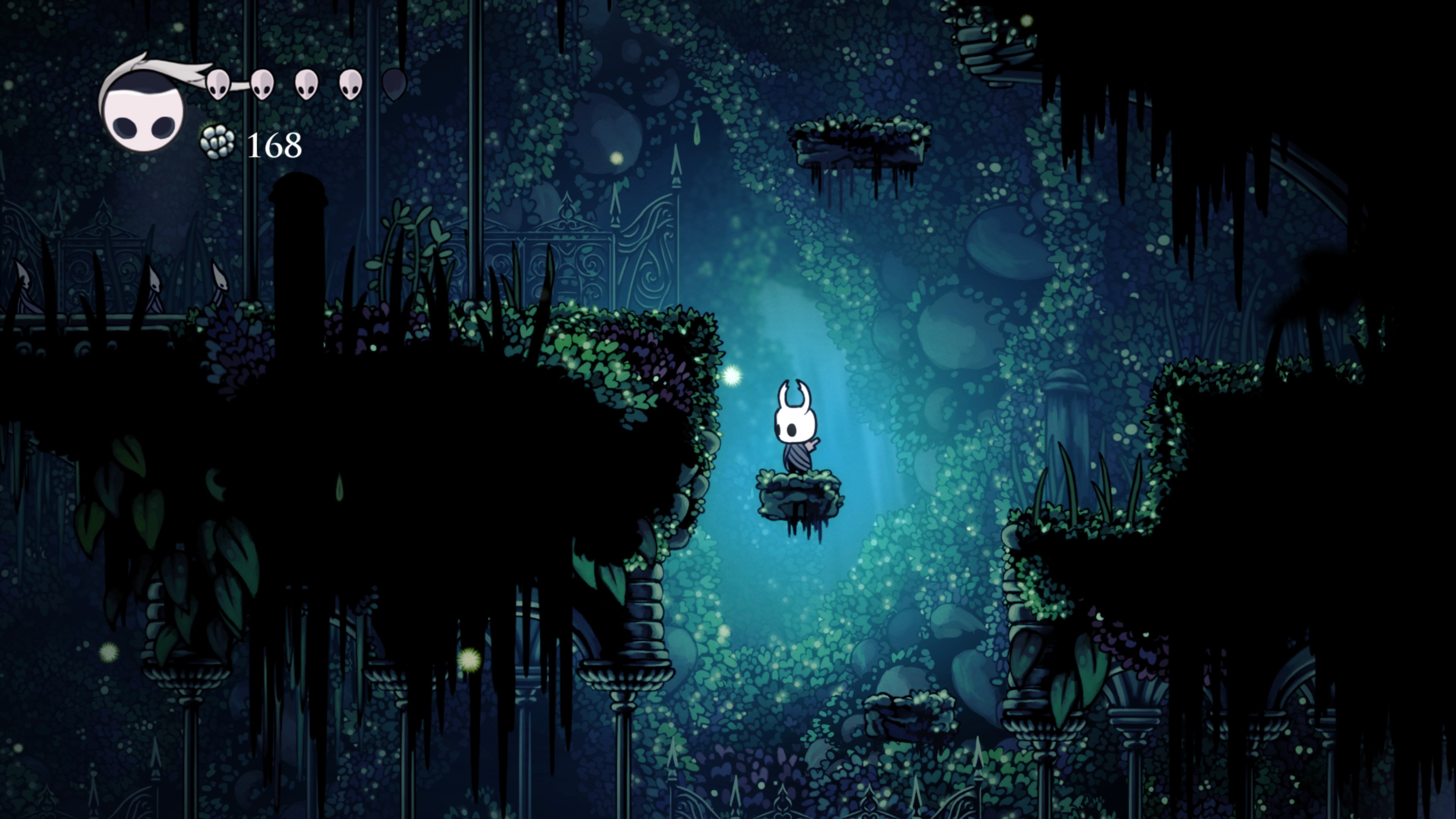 Huvudkaraktären i Hollow Knight står på en liten svävande sten i en mörk grotta täckt av klätterväxter.