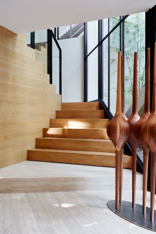 bridging boyd by jolson, a modernist house refreshed with white walls, black framing and details and a overgrown leafy garden seen through large glazing