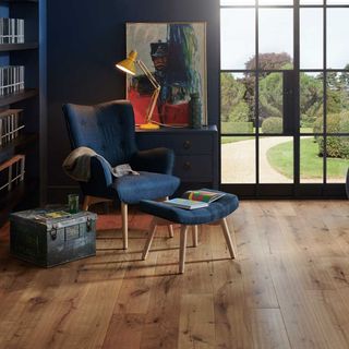 room with blue wall and blue armchair and book shelves and wooden floor