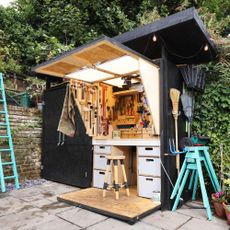 Black garden shed with tiny workshop hidden inside in wood