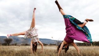 Two girls cartwheeling in the grass