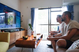 Two men sitting on the living room couch playing a game