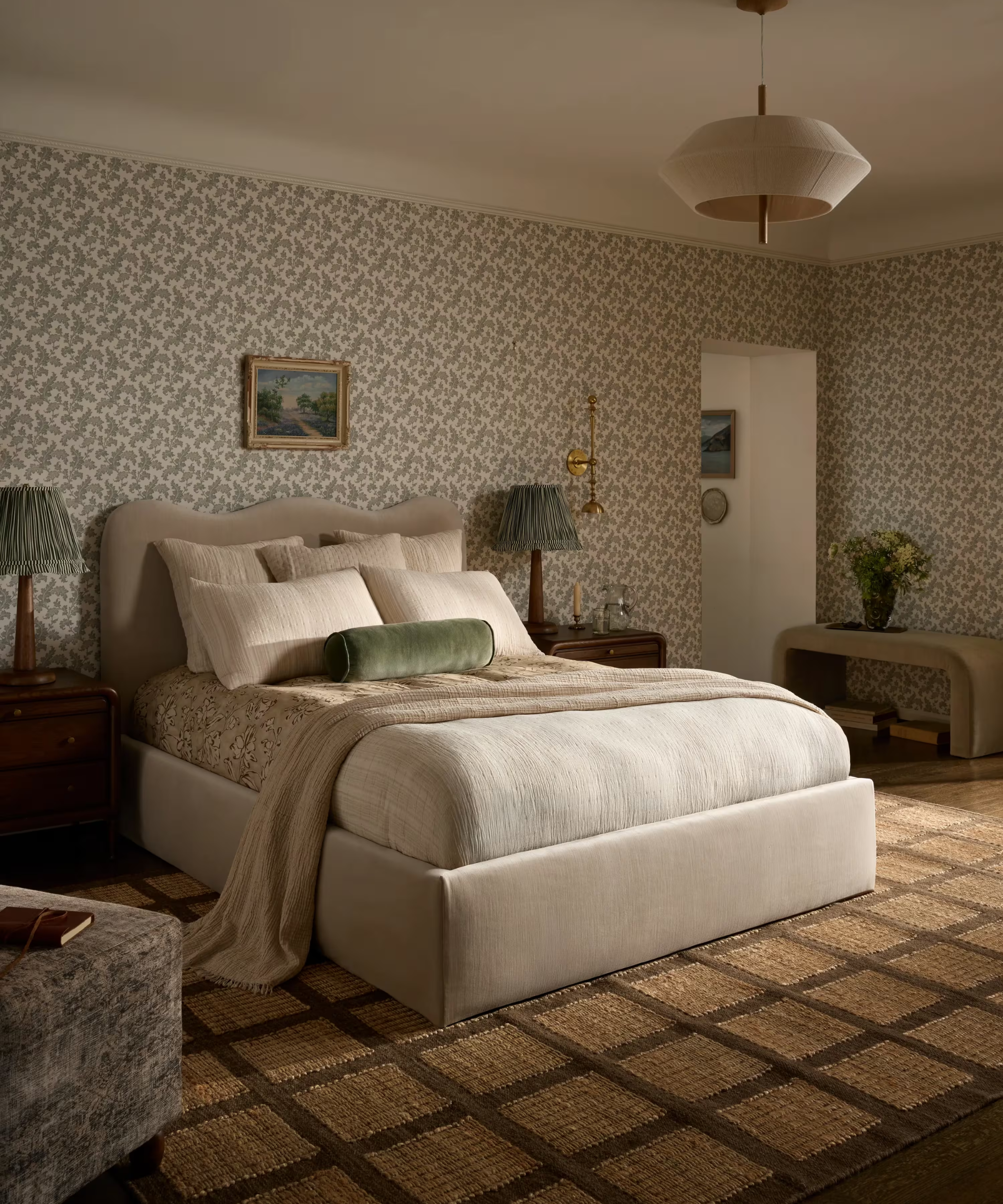 a cozy bedroom with taupe bedding, a jute rug, floral wallpaper, and a pendant from the ceiling