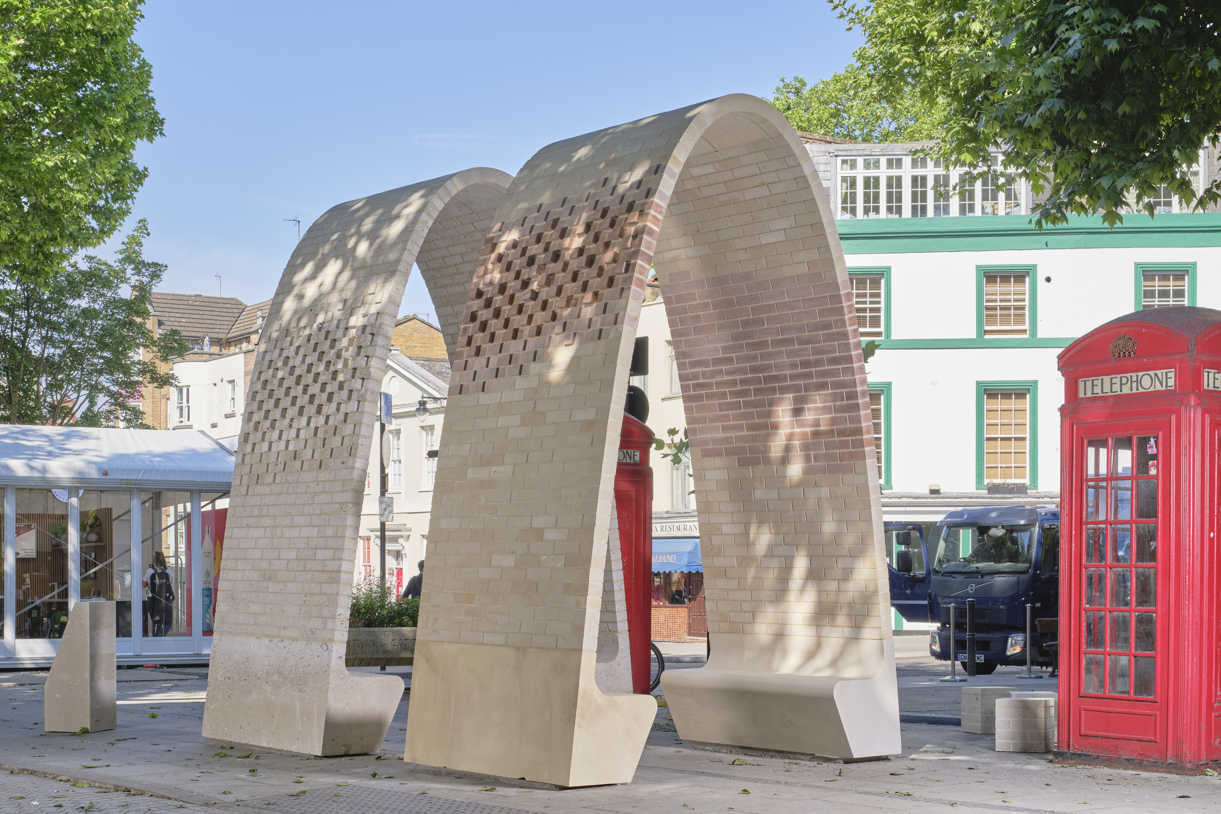 two brick arches in a street next to a phone box